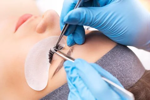 Eyelash extension procedure. The working process of professional beauty master Stock Photos