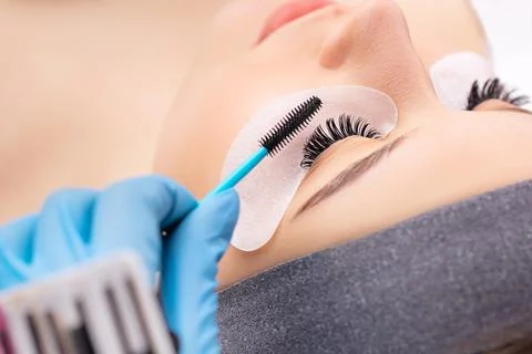 Eyelash extension procedure. The working process of professional beauty master Stock Photos