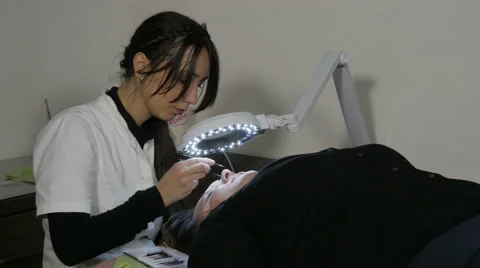 Eyelash extensions. Beautician gluing artificial lashes with tweezers. Make up. Stock Footage 59744089