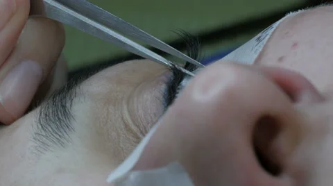 Eyelash extensions. beautician gluing lashes with tweezers, extreme close up. 스톡 동영상 59744083