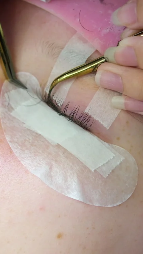 Eyelash extensions process includes applying individual lashes with precision by Stock Footage 323455216