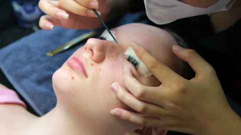 Eyelash extensions process includes applying individual lashes with precision by Stock Footage 324015081