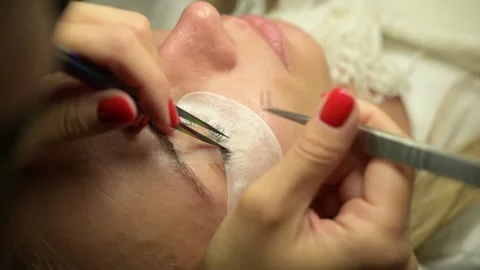 Eyelash extention process, tweezers holding eyelashes close up Stock Footage 163933868