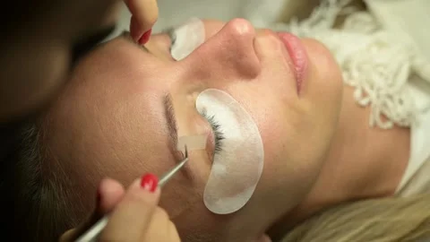 Eyelash extention process, tweezers holding eyelashes close up Stock Footage 166122360