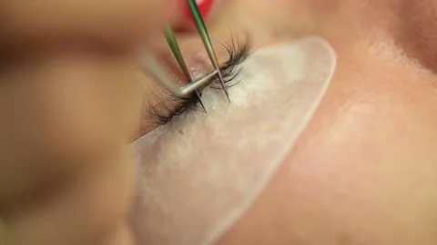 Eyelash extention process, tweezers holding eyelashes close up Stock Footage 166122386