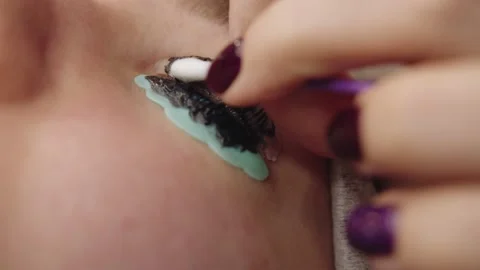 The eyelash lamination master removes the paint with a cotton swab Stockbeeldmateriaal 195320514