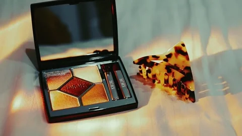 An eyeshadow palette Dior and tortoiseshell hair clip in light ray Stock Footage 308746124