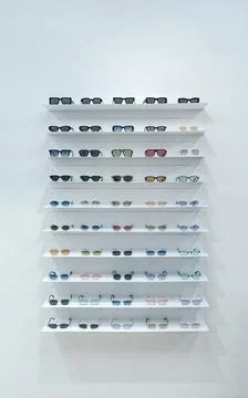 Eyewear display wall, featuring multiple rows of sunglasses on white shelves 库存照片