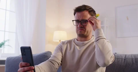 Eyewear problem, man watching phone screen, wrong glasses, feels unwell having Stock Footage 321263527