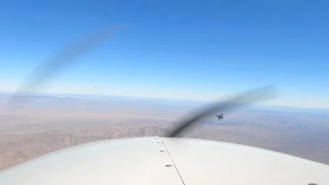 F-16 Fighting Falcon banking right over desert from Cessna light aircraft Stock Footage 263722378
