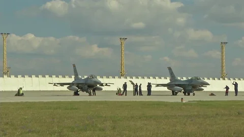 F-16 Fighting Falcon's parked on airstrip in front of blast deflectors Stock Footage 94699196
