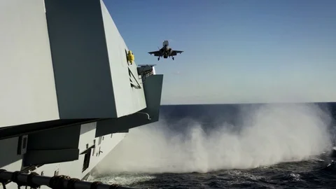 F-35B Lightning creates sea spray on approaching HMS Queen Elizabeth Stock Footage 98927673