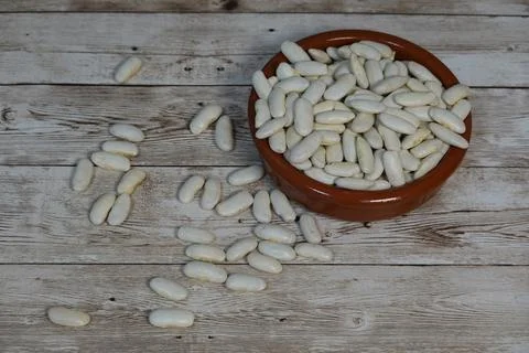 Fabada beans in rustic bowl and scattered on vintage wooden table, preparin.. Stock Photos
