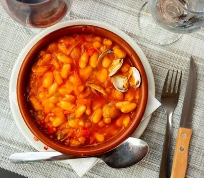 Fabes con almejas of white beans stewed with clams in clay bowl Stock Photos