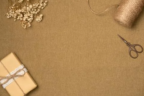 Fabric background with string, scissors, gift box and flowers from above. Vin Stock Photos