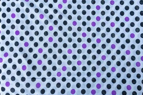 Fabric featuring a repeated pattern of purple and black polka dots on a lig.. Stock Photos