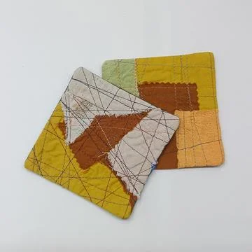 Fabric patchwork pieces with stitched details. Fotos de archivo
