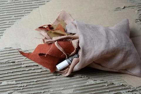 Fabric scraps and thread spool on recycled cardboard Stock Photos