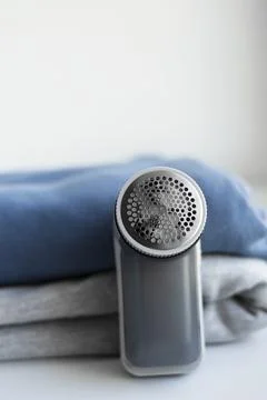 Fabric shaver on stack of sweaters on white background, copy space. Stock Photos