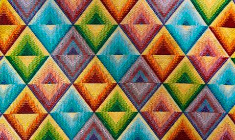 Fabric textile with bright patterns rhombus multi-colored background Stock Photos