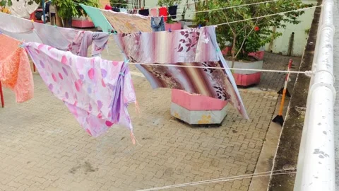 Fabrics dancing in a sunny courtyard breeze 스톡 동영상 323786776