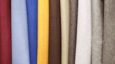 Fabrics of different colors and textures hang on a shop window in a fabric store Stock Footage 97978426