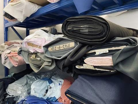 Fabrics textile roller stack on the rack inside the factory tailor Stock Photos