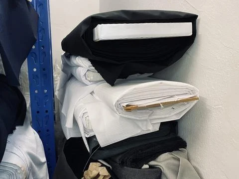 Fabrics textile roller stack on the rack inside the factory tailor Stock Photos