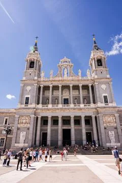 Facade of the Almudena Cathedral with tourists in the square in front Stock Photos