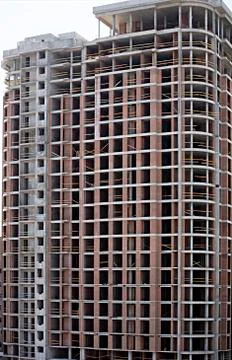 Facade and round corner of a modern concrete building under construction. Stock Photos