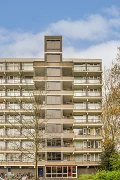 The facade of an apartment building with trees in front Stock Photos