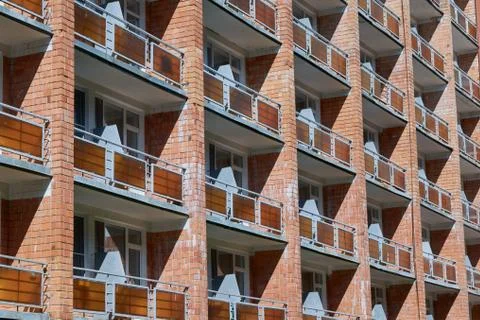 The facade of a brick building with several rows of balconies or loggias. Stock Photos