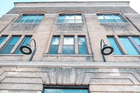 Facade of brick wall building with windows and screens. Looking up perspective Stock Photos