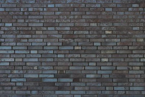 Facade of a brick wall of a gray building with straight rows. Stock Photos