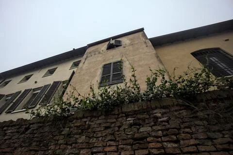 Facade of a building behind a brick wall with a cloudy sky as background Fotos de archivo