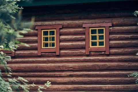 The facade of the building is made of rounded logs with brown dark window frames Fotos de archivo