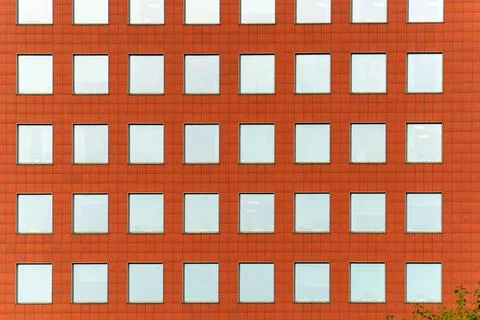 The facade of the building is orange with square windows Stock Photos
