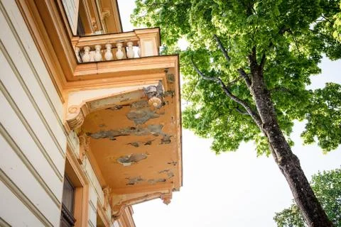 The facade of the building in poor condition. Balcony with peeling paint and Stock Photos