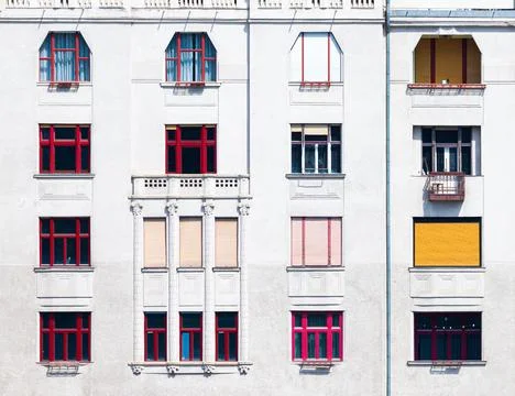 Facade of a building with red window frames of different shapes Stock Photos