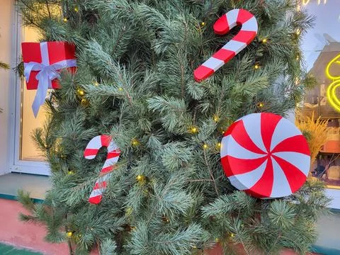 The facade is decorated with Christmas tree branches, and red and white candy Stock Photos