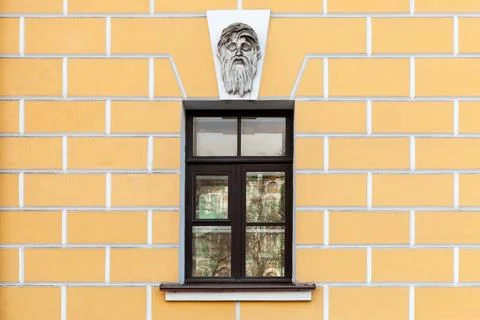 Facade featuring a yellow brick wall, a dark framed window Stock Photos