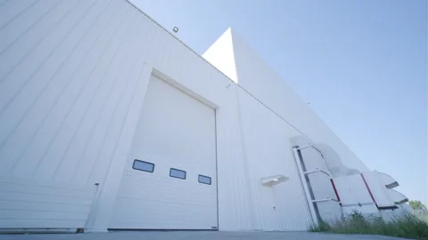 Facade (front view) of a large hangar lined with a metal profile.  Stock Footage 250360388