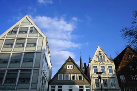 Facade of houses with triangular roofs against a blue cloudy sky Stock Photos
