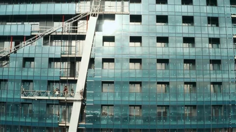Facade of moderm multi-storey glass building under construction with crane on Stock Footage 269056909