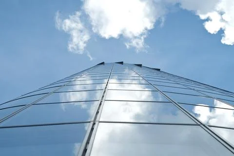 Facade of modern skyscraper with reflection of cloudy sky, low angle shot Stock Photos