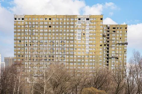 The facade of a multi-storey building under construction against the blue sky Stock Photos