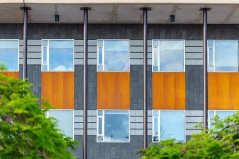 Facade of offices building, repeating windows, steel poles and wooden plank.  Stock Photos