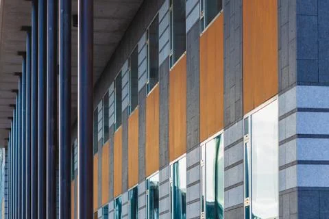 Facade of offices building, repeating windows, steel poles and wooden plank.  Stock Photos