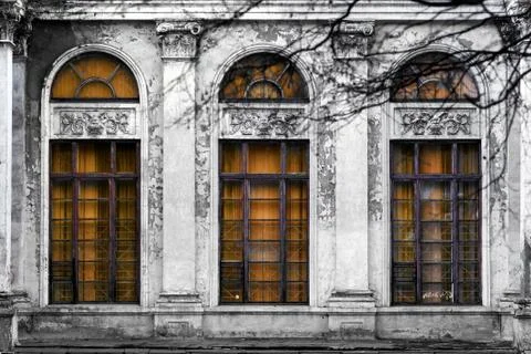 Facade of old abandoned building with three large arched windows of orange gl Stock Photos