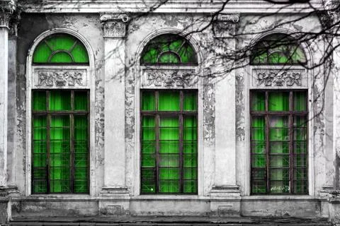 Facade of old abandoned building with three large arched windows of green gla Stock Photos